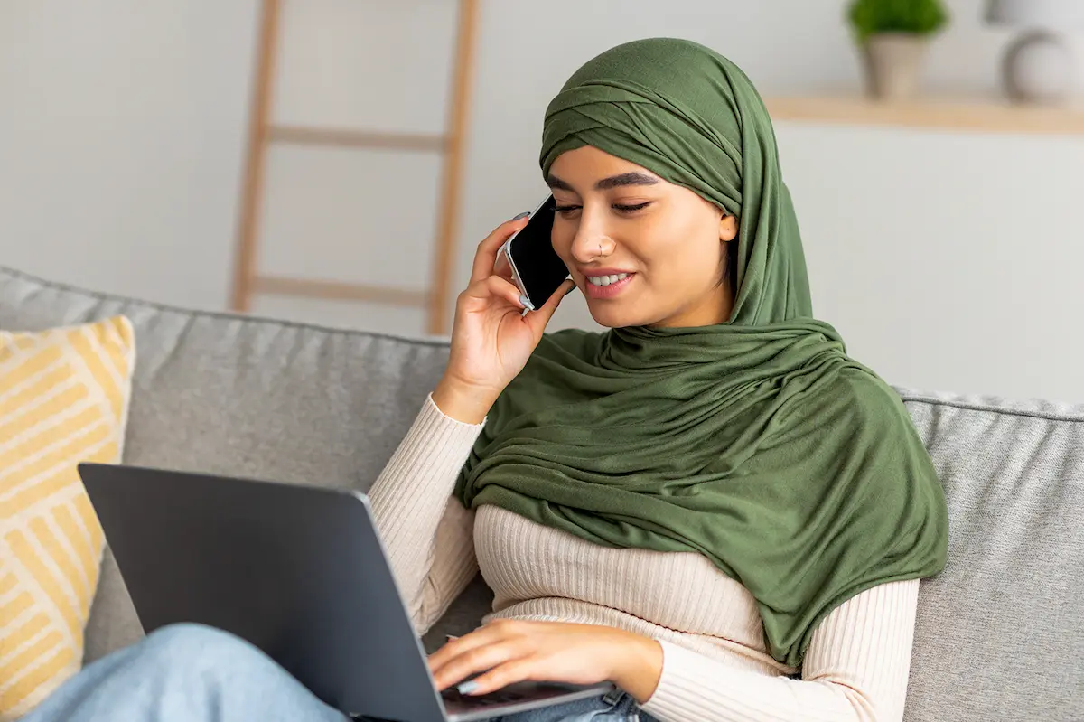 young Arabic woman using laptop and phone.